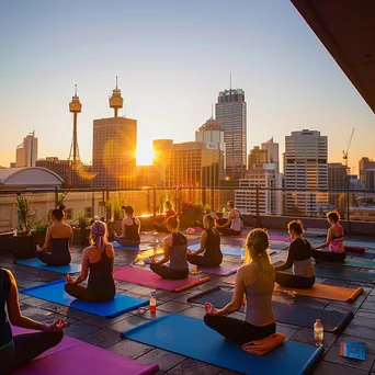 Participants doing yoga on a rooftop at sunrise with city views - Image 3