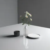 Image of a minimalist dining scene with a single vase holding a bloom - Image 1