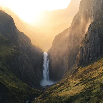 Waterfall cascading into a misty valley illuminated by morning light - Image 1