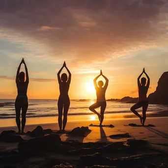 Group of diverse individuals practicing yoga on beach at sunset. - Image 1