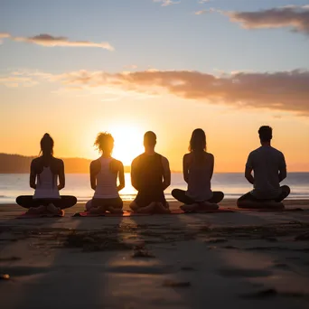 Group of diverse individuals practicing yoga on beach at sunset. - Image 3