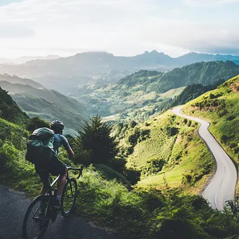 Cyclist pausing at a scenic overlook with lush hills - Image 2