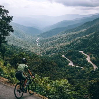 Cyclist pausing at a scenic overlook with lush hills - Image 4