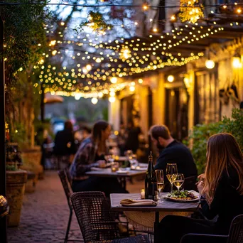 Bistro patio at dusk with fairy lights and couples dining - Image 3