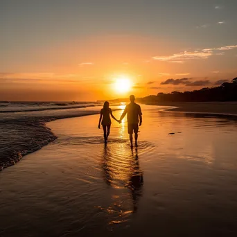 Couple walking along the beach during a vibrant sunset. - Image 4