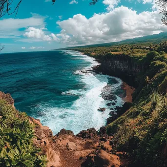 Cliffside view of the beach with dramatic waves and lush greenery under a blue sky. - Image 1