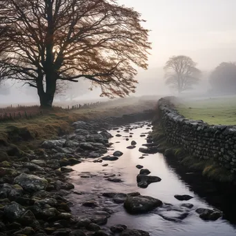 Dry stone wall next to a foggy river in the morning. - Image 1