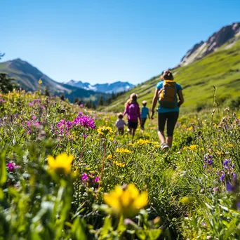 A family hiking through a colorful alpine meadow under clear skies. - Image 1