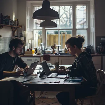 Couple discussing budget with laptop and papers in kitchen - Image 3