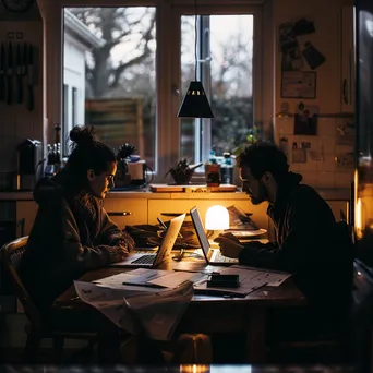 Couple discussing budget with laptop and papers in kitchen - Image 4