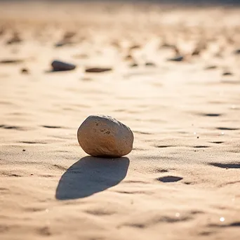 Single smooth stone placed on dry sand. - Image 3