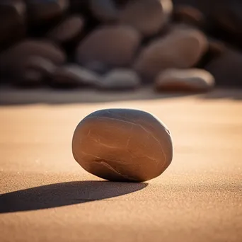 Single smooth stone placed on dry sand. - Image 4