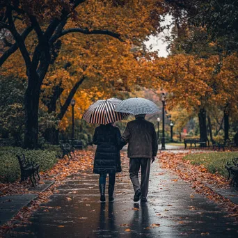 Elderly couple walking under a striped umbrella in autumn rain - Image 4