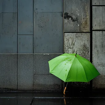 Green umbrella in a grey urban environment during rain - Image 1