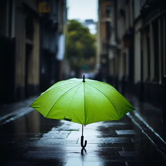 Green umbrella in a grey urban environment during rain - Image 4