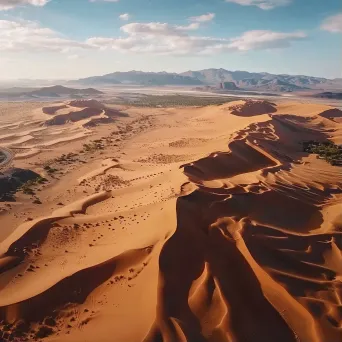 Aerial view of a desert landscape with sand dunes and an oasis - Image 1