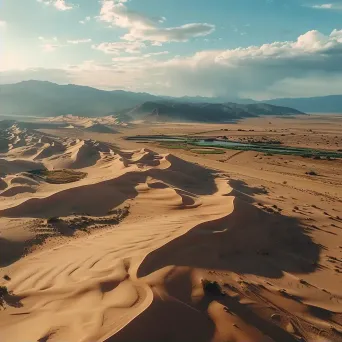 Aerial view of a desert landscape with sand dunes and an oasis - Image 2