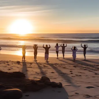 Group practicing yoga on the beach during sunset - Image 1