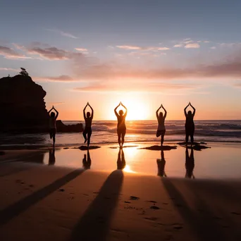 Group practicing yoga on the beach during sunset - Image 4