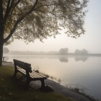 Empty park bench overlooking a serene lake - Image 1