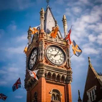 Antique clock tower in town square with flags - Image 1