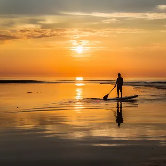 Lone paddleboarder at sunset - Image 1