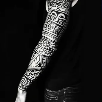 Full-sleeve Polynesian tribal tattoo with bold, black geometric patterns - Image 1