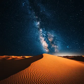 The Milky Way arching over illuminated orange sand dunes in a desert at night. - Image 3