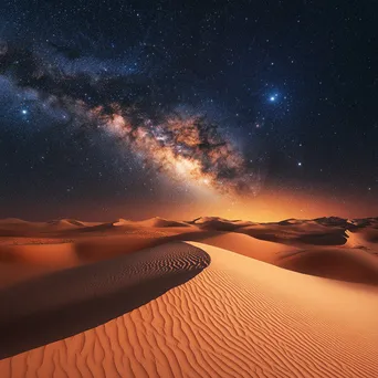 The Milky Way arching over illuminated orange sand dunes in a desert at night. - Image 4