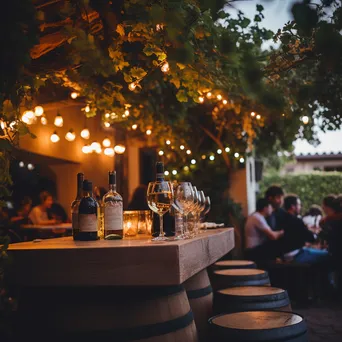 Cozy outdoor wine bar with string lights between grapevines - Image 1