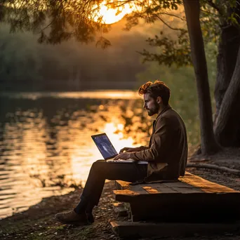 Digital nomad working on a laptop by the lake - Image 2