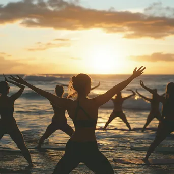 Group of individuals practicing yoga poses on the beach during sunset. - Image 3