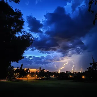 Thunderstorm with lightning during twilight over a city park. - Image 2