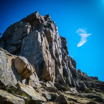 Climbers ascending a granite rock wall with a clear blue sky. - Image 4