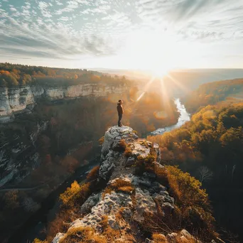 A hiker on a rocky cliff gazing over a sunlit valley - Image 3