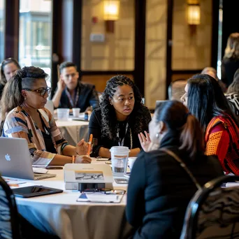 Diverse professionals seated at a round table in a conference session - Image 1