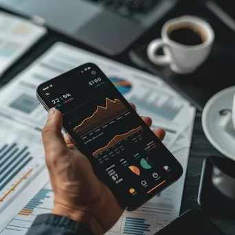 Hand using a phone to check cryptocurrency investment visuals surrounded by financial papers and a coffee cup. - Image 1