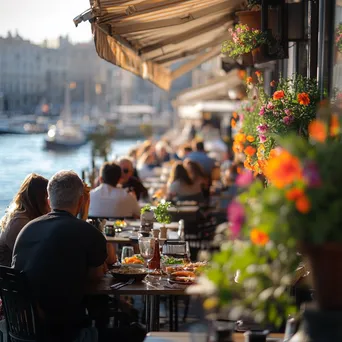 Patrons dining at a seaside café with a view of the harbor and flowers. - Image 4