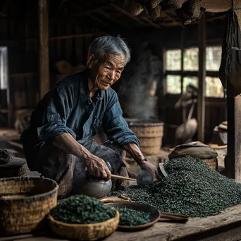 Older farmer demonstrating traditional tea processing in a barn - Image 4