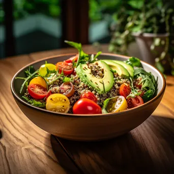 A colorful bowl of quinoa salad with avocado, tomatoes, and arugula on a rustic table. - Image 4