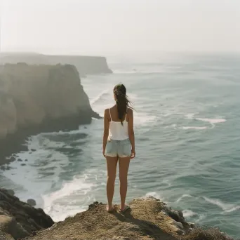 A woman standing on a cliff edge overlooking a vast ocean - Image 2