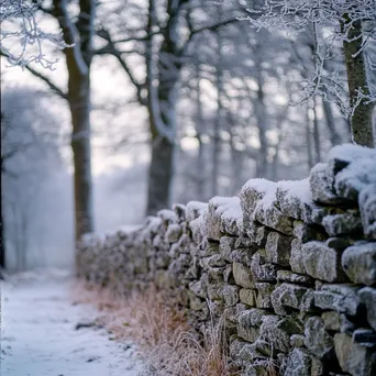 Dry stone wall covered in snow with frosted trees in the background. - Image 2