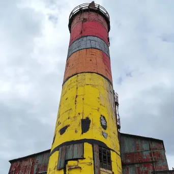 A drab industrial chimney colorfully painted to resemble a giant pencil - Image 3