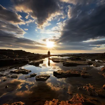 Lone figure walking along rock pools at sunset - Image 2