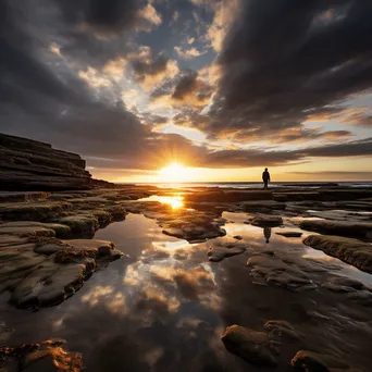 Lone figure walking along rock pools at sunset - Image 4