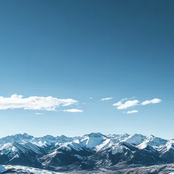 Panoramic view of snow-capped mountain ridges under blue sky - Image 1