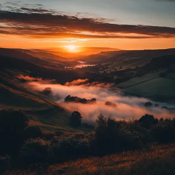 Sunset over a misty valley with warm colors and fog - Image 1