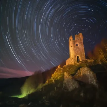 Vibrant star trails painting the sky above ancient castle ruins - Image 4