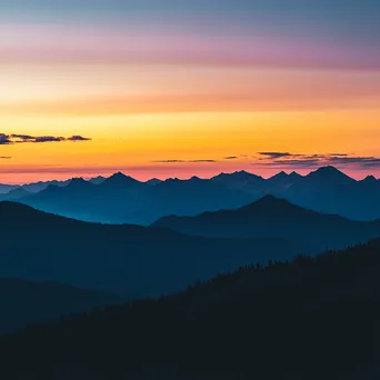 Silhouette of rugged mountain ridges against a colorful sunset - Image 1