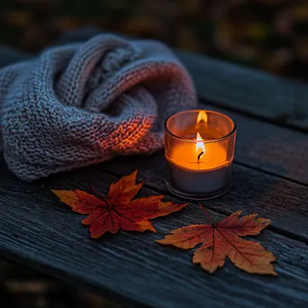 Rustic table adorned with red and orange leaves, a lit candle, and a wool scarf - Image 3